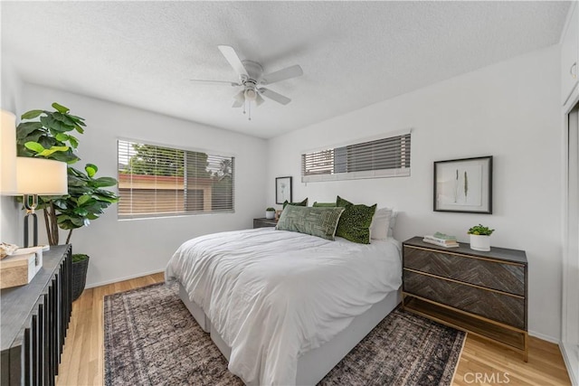 bedroom with light wood-style flooring, a textured ceiling, and ceiling fan