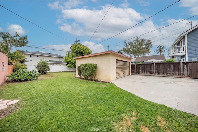 view of yard with a detached garage, an outbuilding, and fence