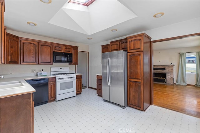 1035 Las Tunas St, Morro Bay, CA 93442 - kitchen featuring black appliances, a sink, a skylight, light countertops, and a fireplace