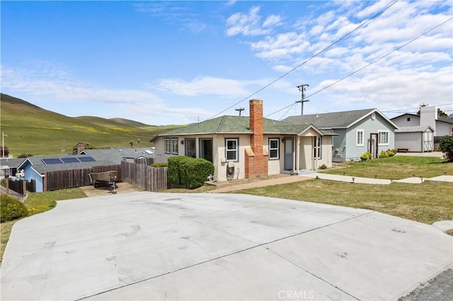 view of front of house with a mountain view, stucco siding, a chimney, fence, and a front yard