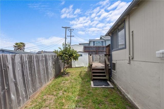 view of yard featuring an outdoor structure, a shed, a deck, and a fenced backyard
