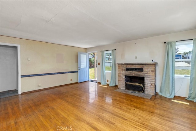 unfurnished living room with baseboards, a fireplace, and light wood-style flooring