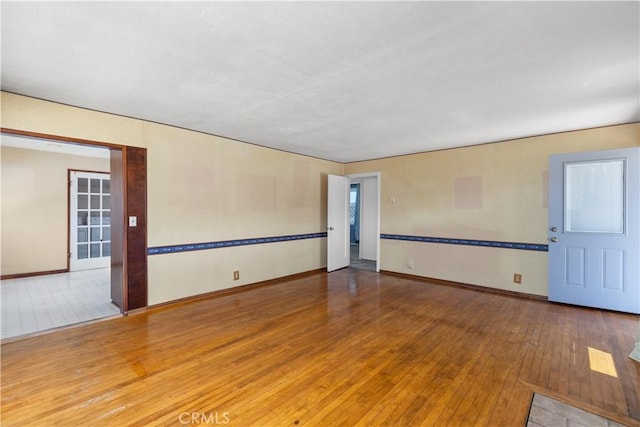 spare room featuring baseboards and hardwood / wood-style flooring