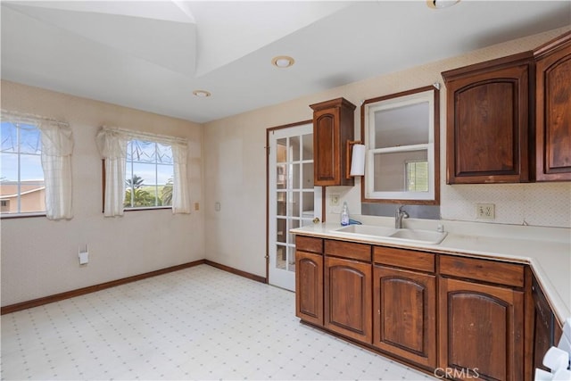 kitchen featuring a sink, light carpet, light countertops, and baseboards