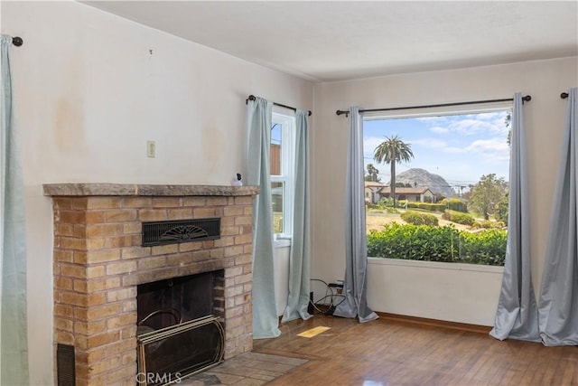 unfurnished living room featuring a wealth of natural light, a fireplace, baseboards, and hardwood / wood-style flooring