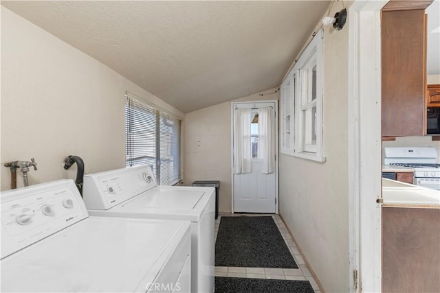 laundry area with washer and dryer, laundry area, a textured ceiling, tile patterned flooring, and baseboards