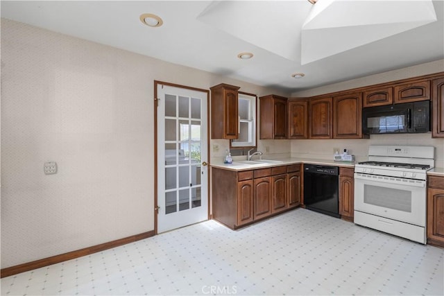 kitchen with black appliances, light countertops, baseboards, light floors, and a sink