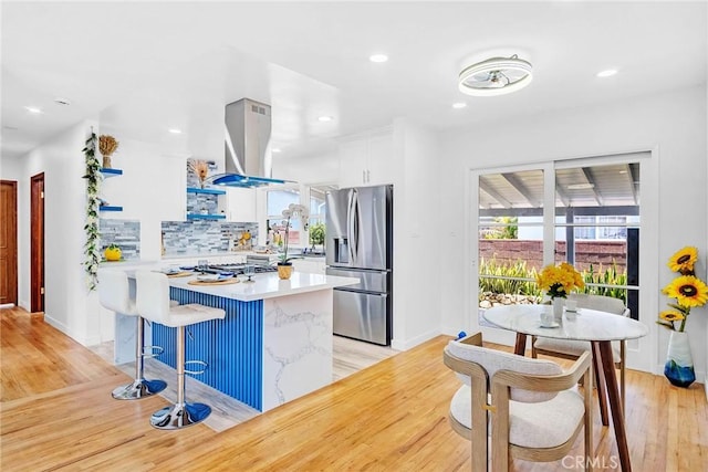 1521 249th St, Harbor City, CA 90710 - kitchen with stainless steel fridge with ice dispenser, island exhaust hood, light wood-style flooring, light countertops, and healthy amount of natural light
