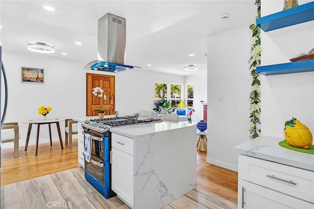 1521 249th St, Harbor City, CA 90710 - kitchen with island range hood, range with two ovens, light wood-style floors, baseboards, and white cabinets