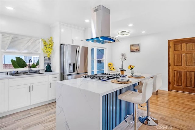 1521 249th St, Harbor City, CA 90710 - kitchen with island range hood, stainless steel fridge, a sink, a kitchen breakfast bar, and light wood-style flooring