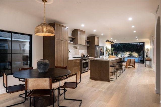 kitchen with a kitchen breakfast bar, light wood-style flooring, premium appliances, and a kitchen island
