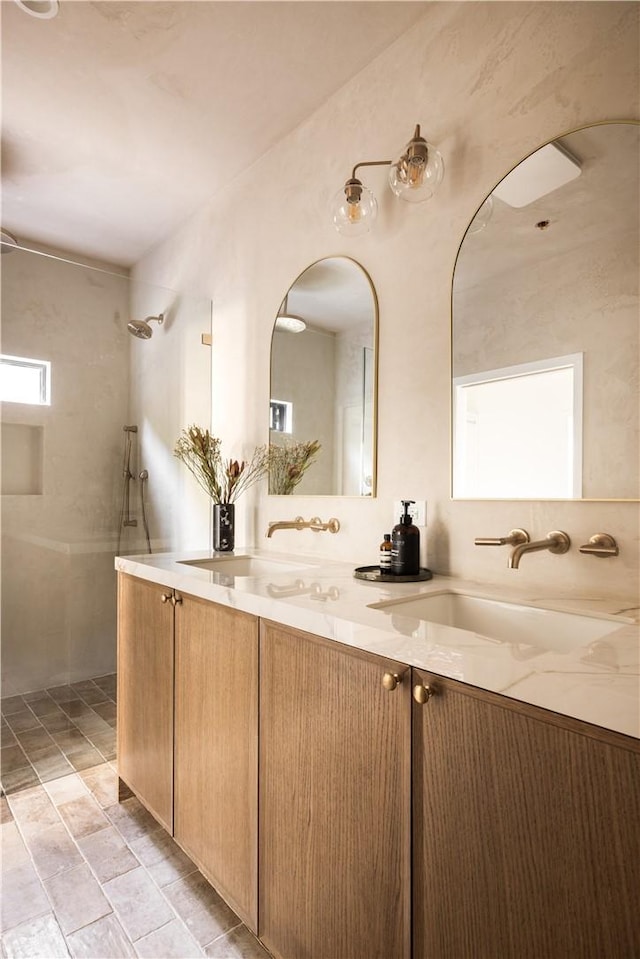 bathroom featuring a sink, double vanity, and tiled shower