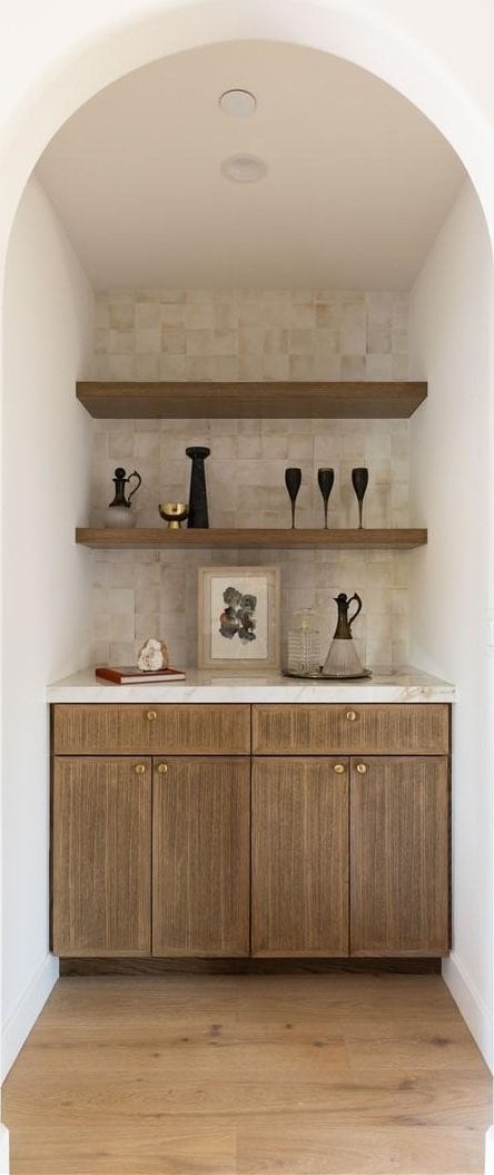 bar featuring arched walkways, light wood finished floors, and baseboards