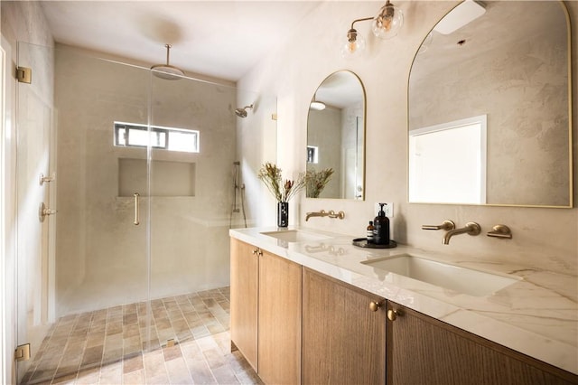 full bathroom featuring double vanity, a stall shower, and a sink