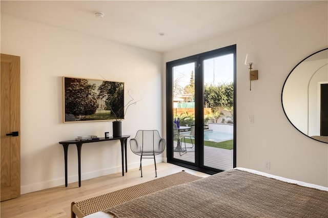 bedroom with access to exterior, light wood finished floors, and baseboards