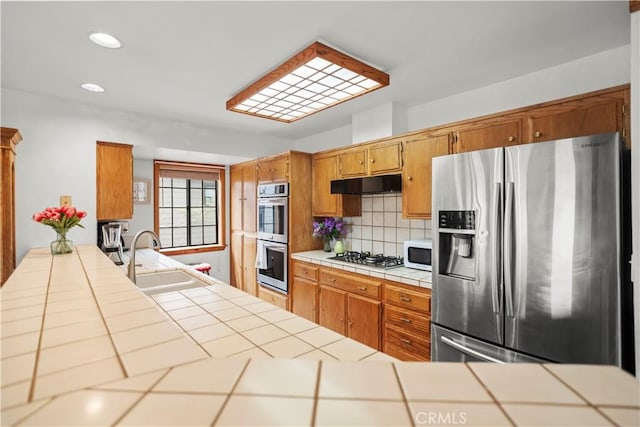 2116 Ironwood Ct, Pine Mountain Club, CA 93222 - kitchen featuring under cabinet range hood, backsplash, tile countertops, a sink, and appliances with stainless steel finishes