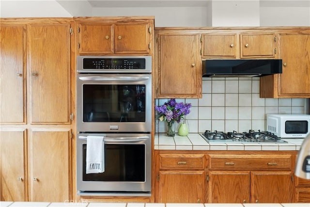2116 Ironwood Ct, Pine Mountain Club, CA 93222 - kitchen featuring double oven, white microwave, under cabinet range hood, gas stovetop, and tile counters
