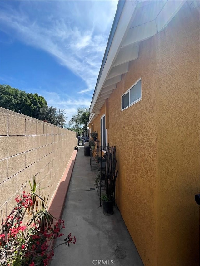 view of side of home featuring stucco siding and fence