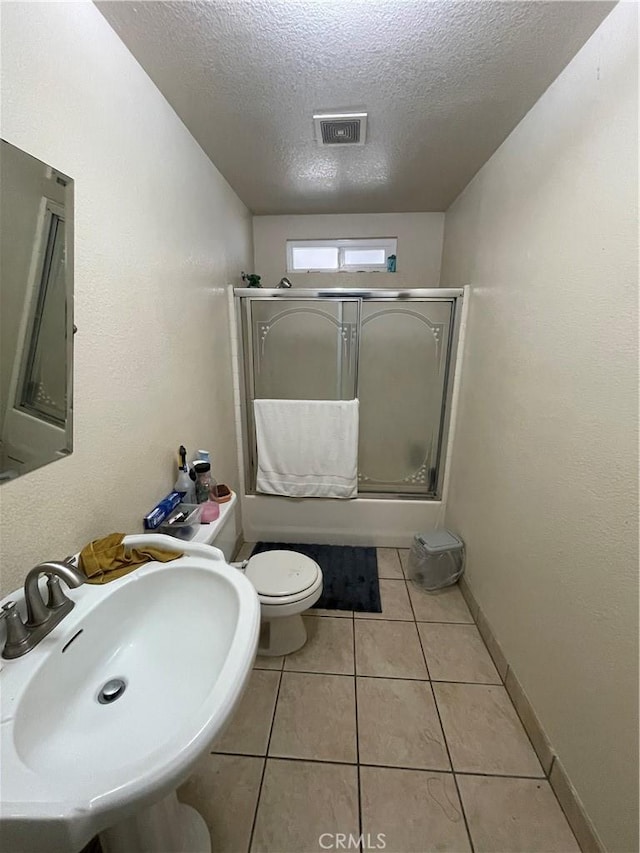bathroom featuring tile patterned flooring, visible vents, toilet, a sink, and a textured ceiling