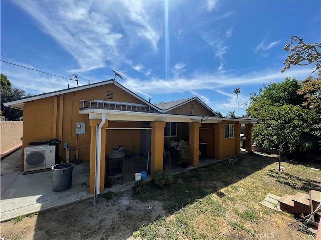 rear view of property with a patio area, ac unit, a yard, and stucco siding