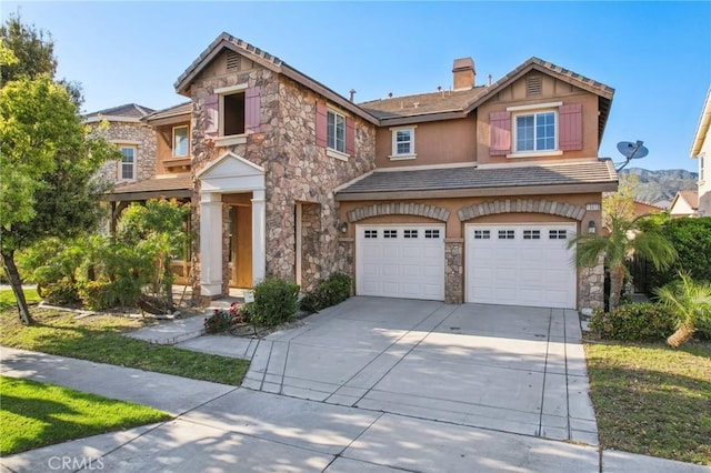 view of front of property with stone siding, a chimney, concrete driveway, a garage, and stucco siding