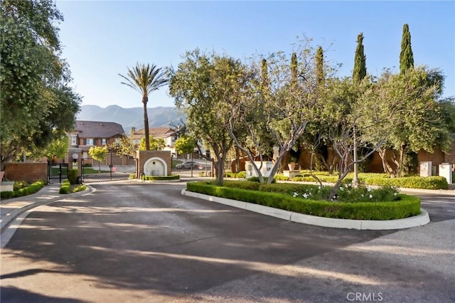 view of street with a gate, sidewalks, curbs, a mountain view, and a residential view