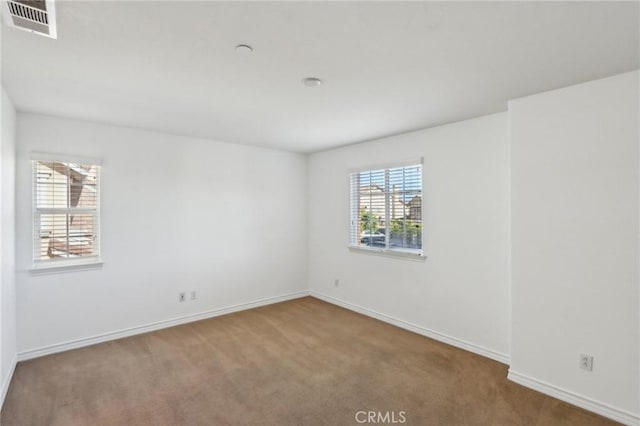 spare room with baseboards, visible vents, and carpet