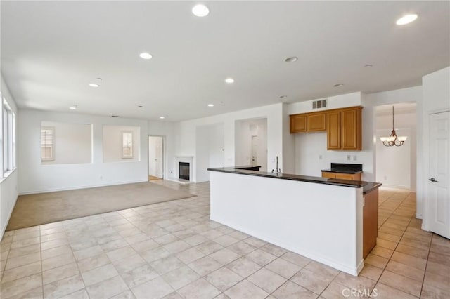 kitchen featuring a chandelier, recessed lighting, dark countertops, and a glass covered fireplace