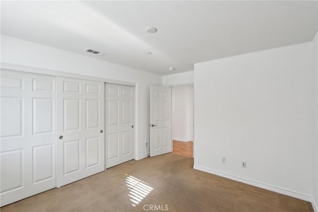 unfurnished bedroom with baseboards, visible vents, carpet, and a closet