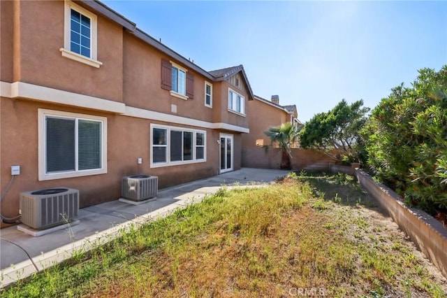 rear view of property with stucco siding, a fenced backyard, central AC, and a patio