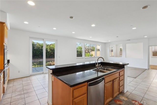 kitchen with a kitchen island with sink, light tile patterned floors, stainless steel appliances, and a sink