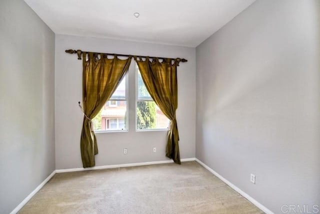 empty room featuring baseboards and light colored carpet