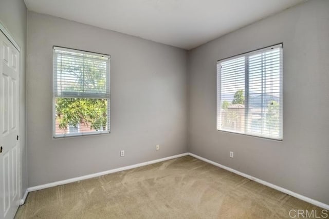 unfurnished room with baseboards and light carpet