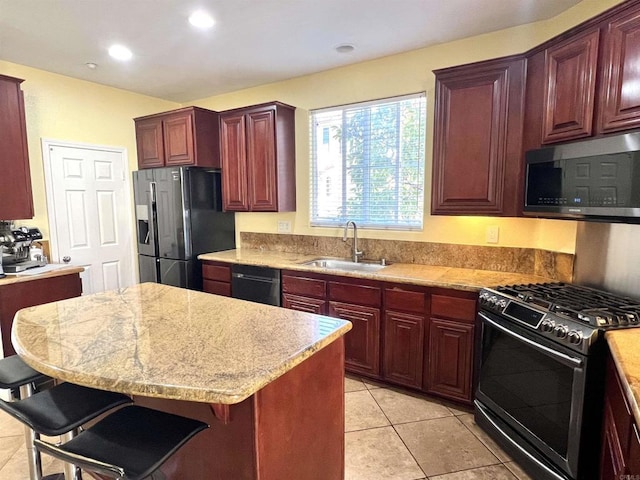kitchen featuring a breakfast bar area, reddish brown cabinets, a sink, and stainless steel appliances