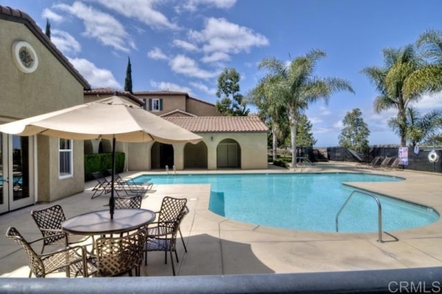 pool with fence, french doors, and a patio