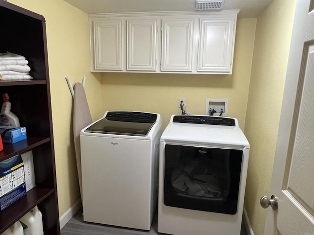 laundry area with cabinet space, washing machine and dryer, visible vents, baseboards, and wood finished floors