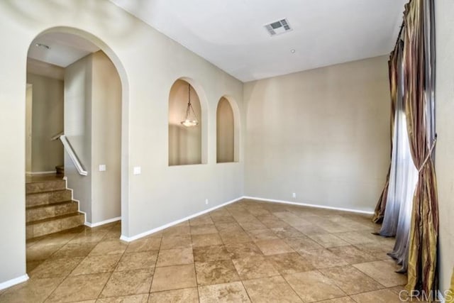 unfurnished room featuring stairs, visible vents, and baseboards