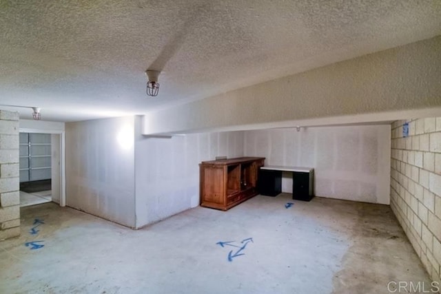 finished below grade area featuring a textured ceiling and concrete block wall