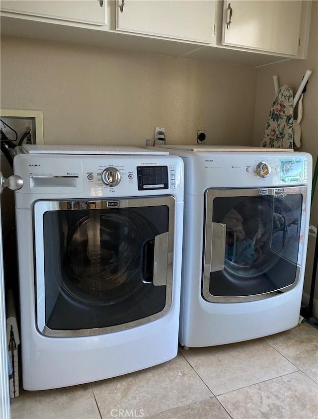 washroom with separate washer and dryer, light tile patterned floors, and cabinet space