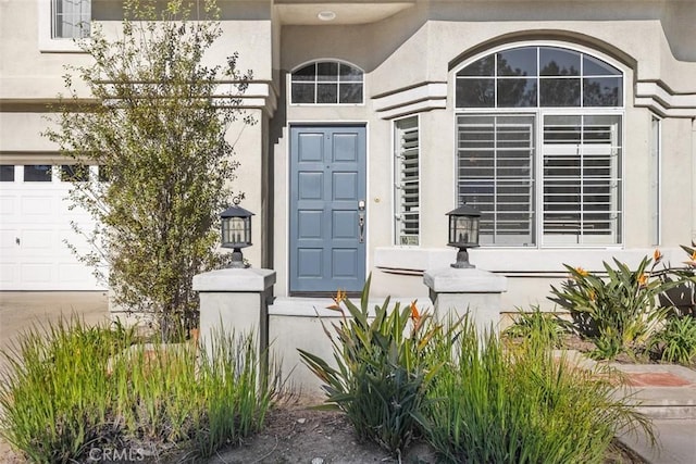 entrance to property with stucco siding and a garage
