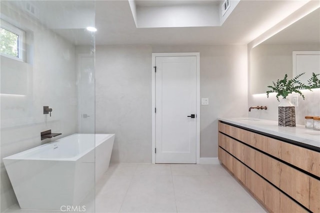 full bath with tile patterned floors, a sink, double vanity, visible vents, and a freestanding tub