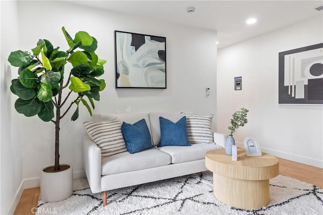 living area with baseboards, wood finished floors, and recessed lighting