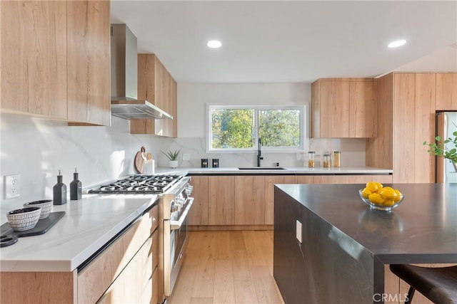 kitchen featuring modern cabinets, wall chimney range hood, stainless steel gas range, and a sink
