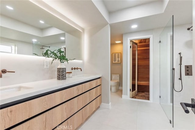 bathroom featuring a sink, double vanity, toilet, tile patterned flooring, and a walk in shower