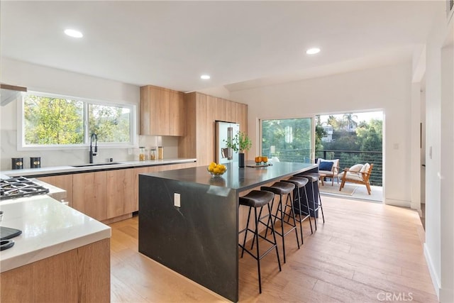 kitchen with modern cabinets, a kitchen breakfast bar, light brown cabinetry, and a sink