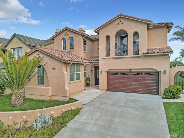 mediterranean / spanish house featuring stucco siding, a tiled roof, a balcony, and a garage