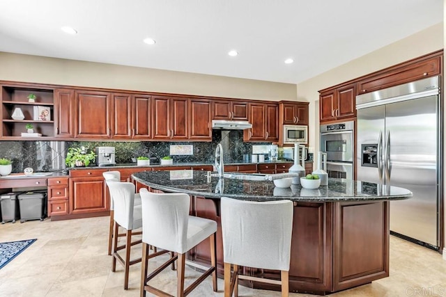 10495 Abalone Lndg, San Diego, CA 92130 - kitchen featuring built in appliances, backsplash, an island with sink, dark stone counters, and recessed lighting