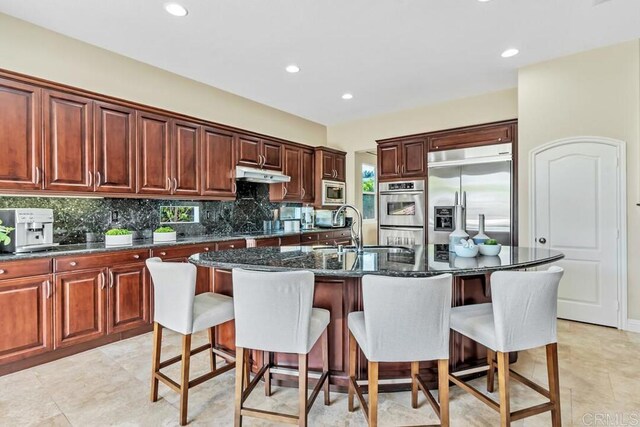 10495 Abalone Lndg, San Diego, CA 92130 - kitchen with built in appliances, under cabinet range hood, a sink, backsplash, and a kitchen island with sink