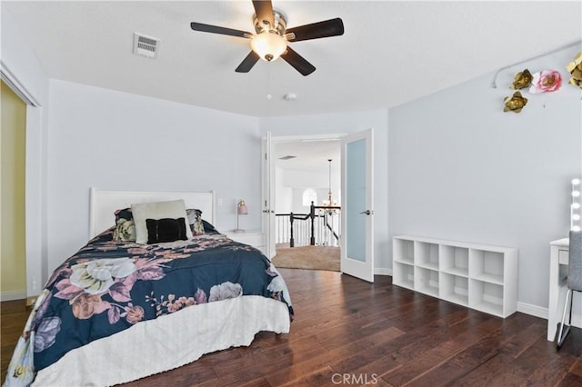 bedroom featuring baseboards, hardwood / wood-style floors, visible vents, and ceiling fan with notable chandelier