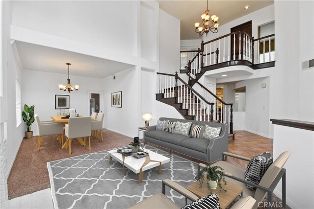 living room featuring a chandelier, stairway, a high ceiling, and visible vents